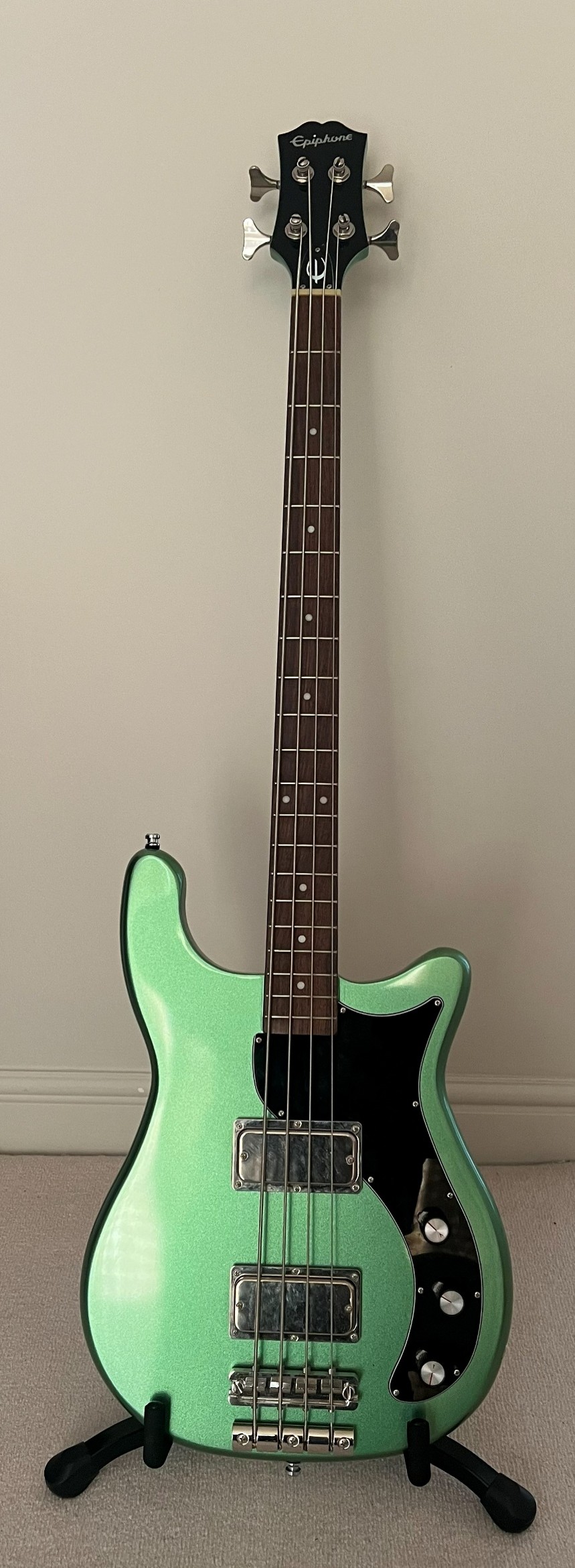 In‑room photo of Lottie’s green Epiphone Embassy bass guitar on a stand.